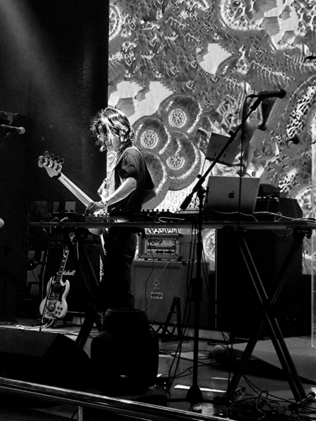 The photo shows the sound artist hollowmist on stage. He is playing the bass with different live electronics.