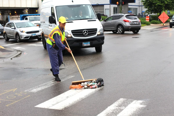 On the photo you see the artists on the street dressed up as a trashman. The artist sweeps with the broom different objects.
