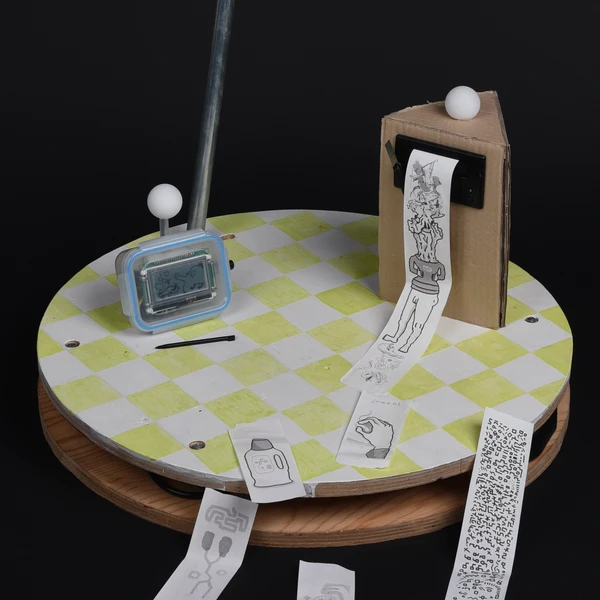 An image of Igor Bobeldijk's novel communication device its placed on a round plate. Its made out of two parts. A drawing part and a printing part.